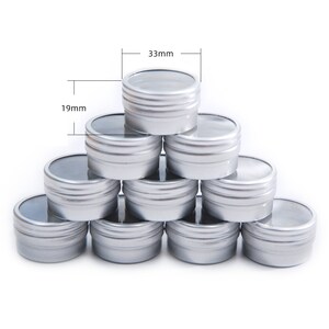 May include: Ten silver metal containers with clear lids stacked in a pyramid shape. The containers are 33 mm tall and 19 mm wide.