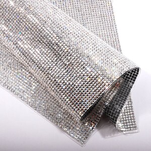 May include: A sheet of clear, iridescent, square-shaped rhinestones on a mesh backing. The rhinestones are arranged in a grid pattern.