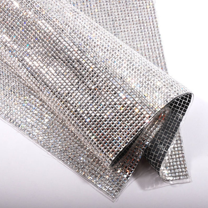 May include: A sheet of clear, iridescent, square-shaped rhinestones on a mesh backing. The rhinestones are arranged in a grid pattern.