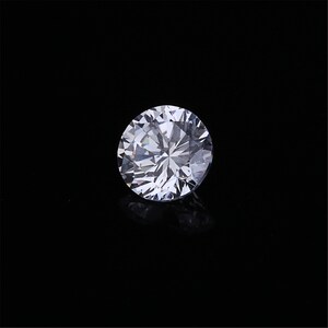 Pu&ograve; includere: Un diamante rotondo trasparente con molte sfaccettature, su uno sfondo nero.