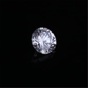 Pu&ograve; includere: Un grande diamante rotondo e trasparente con molte sfaccettature.
