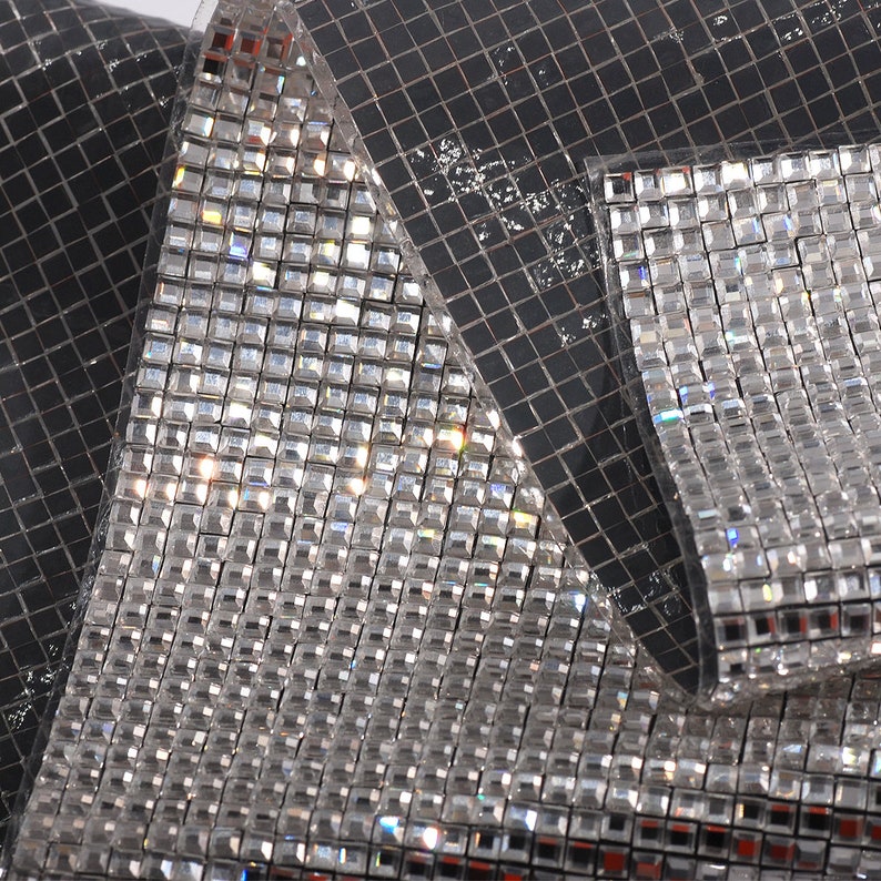 May include: A sheet of clear, square-shaped rhinestones, arranged in a grid pattern. The rhinestones are reflective and have a slight iridescent quality.