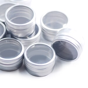 May include: A group of silver metal containers with clear plastic lids. The containers are stacked on top of each other and are all the same size.