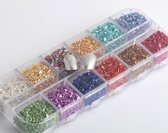 Pode incluir: Um recipiente de plástico transparente com 12 compartimentos cheios de flocos de glitter de diferentes cores. O recipiente está cheio de várias cores, incluindo prata, ouro, vermelho, verde, azul e roxo. Duas ferramentas de arte para unhas prateadas estão incluídas.
