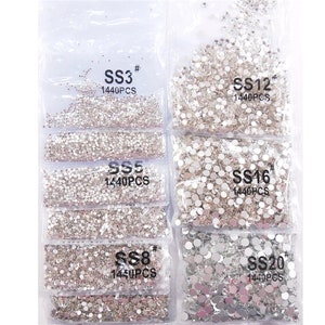 May include: Assortment of clear rhinestone crystals in various sizes, packaged in clear plastic bags. Each bag is labeled with the size of the rhinestones, such as SS3, SS5, SS8, SS12, SS16, and SS20, and the quantity, 1440PCS.