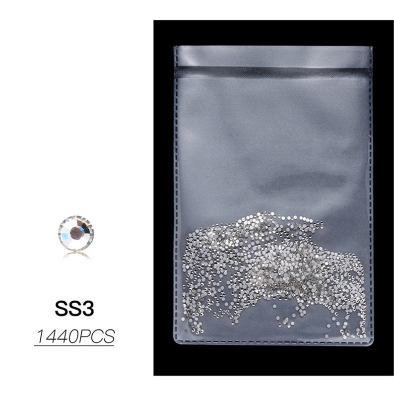 May include: A clear plastic bag filled with small, clear rhinestones. The bag is labeled "SS3 1440PCS". A single rhinestone is shown next to the bag.