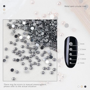 Puede incluir: Una imagen de primer plano de remaches semi-circulares de metal plateado para decoración de uñas. Los remaches están dispersos sobre una superficie blanca. A la derecha de la imagen se muestra una uña negra con remaches plateados de diferentes tamaños. El texto "Remache semi-circular de metal" y las medidas en milímetros se muestran junto a la uña.