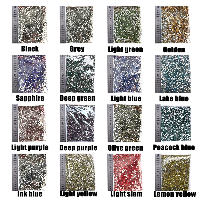 May include: Assortment of 16 small bags of colorful rhinestones, each bag labeled with a color name: Black, Grey, Light Green, Golden, Sapphire, Deep Green, Light Blue, Lake Blue, Light Purple, Deep Purple, Olive Green, Peacock Blue, Ink Blue, Light Yellow, Light Siam, Lemon Yellow.
