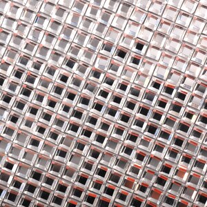 May include: A silver-colored mesh fabric with a grid pattern of small square mirrors. The fabric has a slight sheen and is made of a durable material.