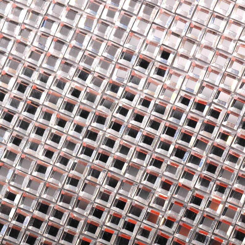 May include: A silver-colored mesh fabric with a grid pattern of small square mirrors. The fabric has a slight sheen and is made of a durable material.