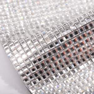 May include: A sheet of clear, square-shaped rhinestones, arranged in a grid pattern. The rhinestones have a reflective surface and create a shimmering effect.