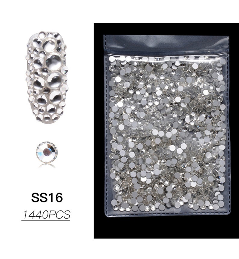 May include: A clear plastic bag filled with small, round, clear rhinestones. The rhinestones are in various sizes and are perfect for nail art, crafts, and jewelry making. The bag also includes a close-up image of a single rhinestone and a larger image of rhinestones arranged in a cluster. The text "SS16 1440PCS" is printed below the images.