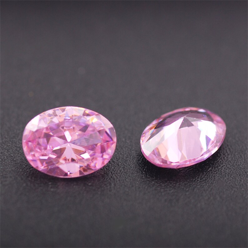May include: Two pink oval-shaped gemstones with a faceted cut.