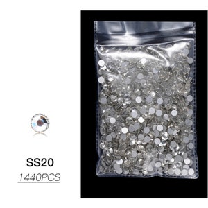 May include: A clear plastic bag filled with small, clear rhinestones. The bag is labeled "SS20 1440PCS".