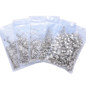 May include: Five clear plastic bags filled with silver rhinestones of various sizes.
