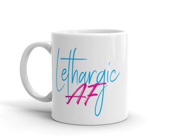 May include: White ceramic mug with a blue and pink design. The text on the mug reads "Lethargic AF".