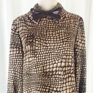 May include: A brown and beige dress with a snakeskin pattern. The dress has a collared neckline and a bow at the collar.