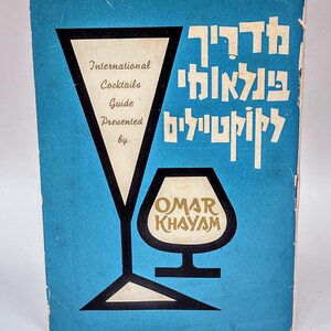 May include: A blue book cover featuring a stylised image of two glasses and the text "International Cocktails Guide Presented by Omar Khayyam" in gold lettering.