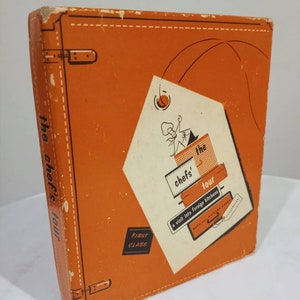 May include: An orange book cover with a cartoon chef on it. The book is titled "The Chef's Tour: A Visit into Foreign Kitchens".