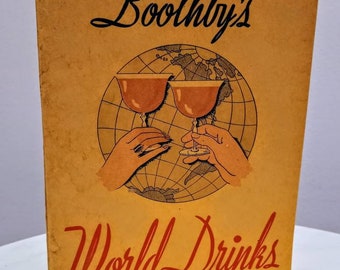 May include: A vintage yellow booklet titled "Cocktail Bill" Boothby's World Drinks and How to Mix Them. The cover features a cartoon illustration of two hands holding up glasses of red liquid against a world map.
