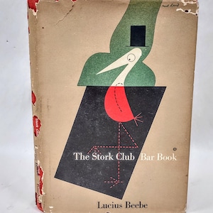 Puede incluir: Portada de libro vintage para "The Stork Club Bar Book" de Lucius Beebe. La portada presenta una ilustración estilizada de cigüeña en rojo, negro, verde y blanco. El libro tiene una cubierta desgastada de color beige con detalles rojos en el lomo.