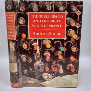 May include: A book cover with a red title that reads "The Noble Grapes and the Great Wines of France" by André L. Simon. The cover features a wine cellar with bottles of wine and a lit candle.