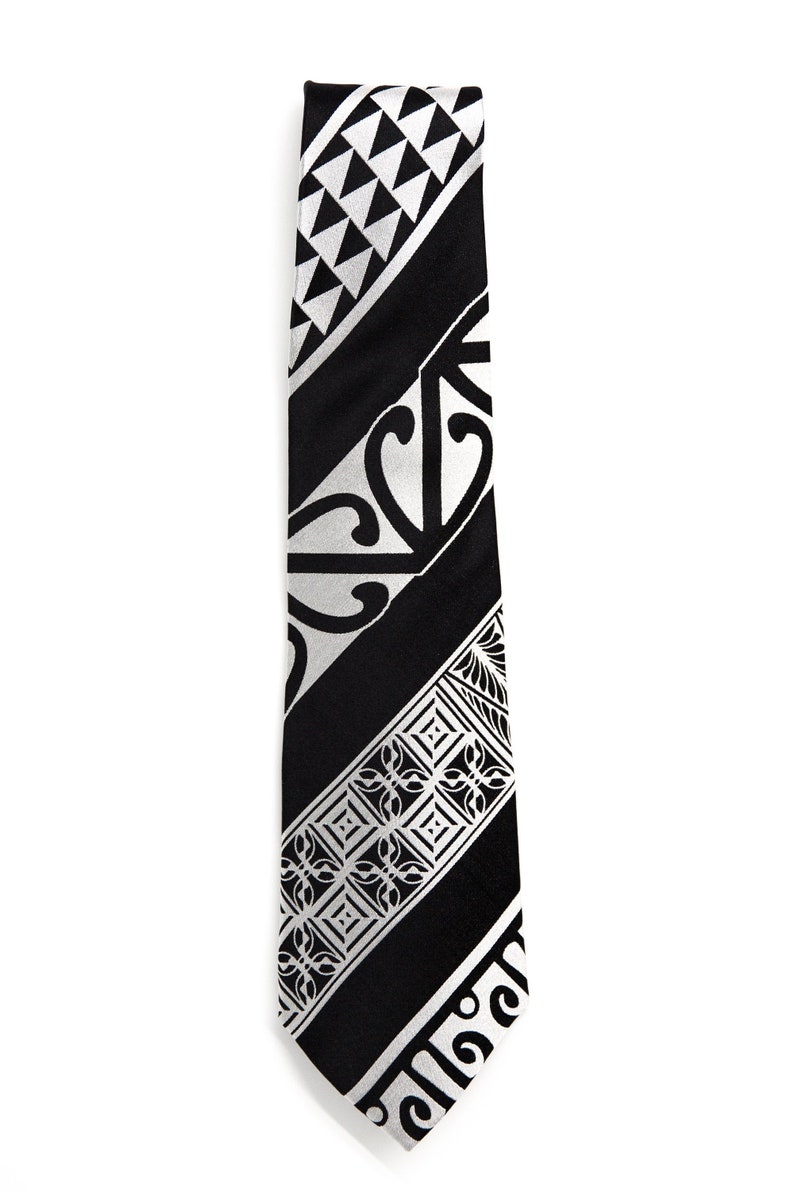May include: A black tie with a silver patterned design featuring geometric shapes and swirls.