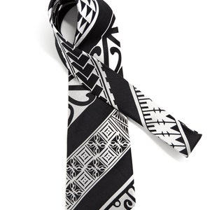 May include: A black and white patterned tie with a geometric design. The tie is made of a silky material and has a pointed end.