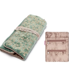 May include: A sage green velvet jewellery roll featuring gold embroidered vine patterns and a matching ribbon tie, displayed alongside an open, rectangular, satin-lined interior organiser with two horizontal zippered pockets and a small brand tag.