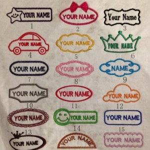 May include: A collection of 18 embroidered iron-on patches with different designs and colours. The patches feature the text "YOUR NAME" in various fonts and styles. Some patches include a car, a crown, a smiley face, a bow, and a cloud.