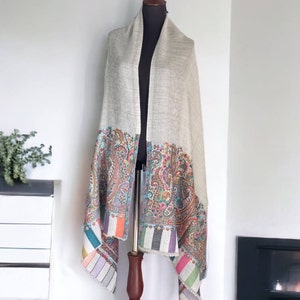 May include: A light gray shawl with a colorful paisley pattern border. The shawl is made of soft, luxurious fabric and is perfect for adding a touch of elegance to any outfit.