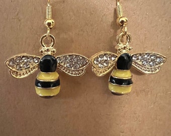 Può includere: Orecchini a forma di ape dorati con smalto nero e giallo e strass trasparenti.