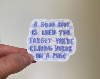 May include: A purple and white checkered sticker with the text "A good book is when you forget you're reading words on a page".