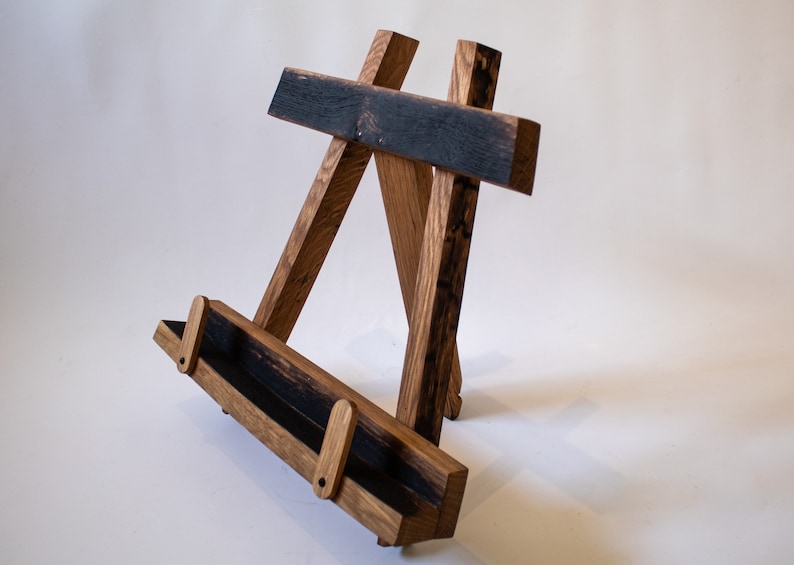 May include: A wooden easel made from reclaimed wood with a dark brown stain. The easel has a shelf for displaying items.