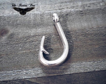 May include: Silver-toned metal fishing hook charm. The hook is about 2 inches long and has a sharp point.