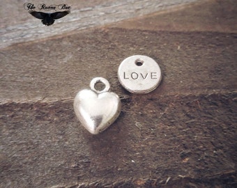 May include: Two silver charms, one shaped like a heart and the other a circle with the word "LOVE" engraved on it.