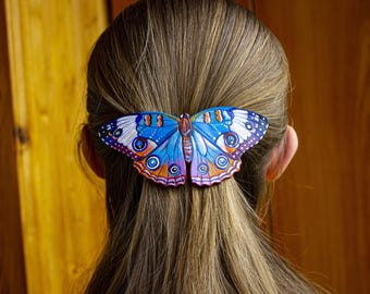 May include: A colorful butterfly hair clip, featuring shades of blue, orange, and purple, is secured in the hair. The butterfly design has intricate details and is positioned at the back of the head, adding a decorative touch to the hairstyle.