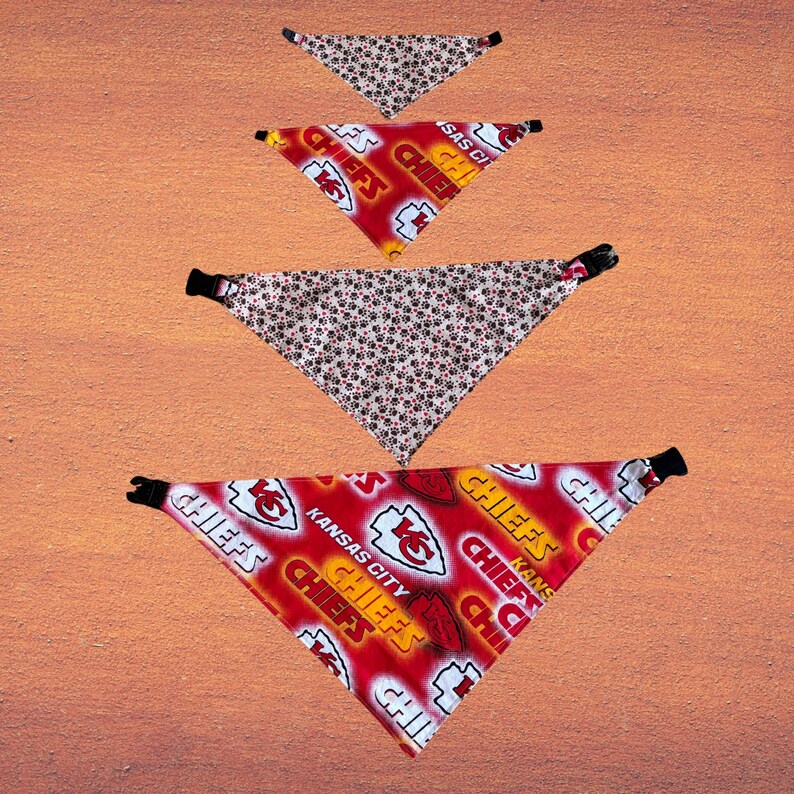 May include: Four triangular pet bandanas. Two are red with "Chiefs" and "Kansas City" text and logos. The other two are white with a repeating pattern of red paw prints and black accents. Each bandana has a black buckle.