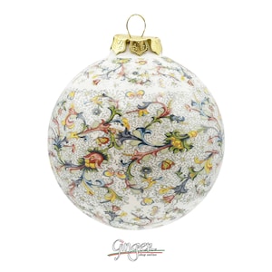 May include: A white ceramic Christmas ornament with a gold top and a colorful floral pattern.