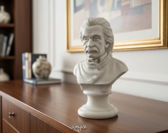 May include: A white marble-style bust of Albert Einstein featuring his signature wild hair and mustache, set on a circular pedestal base. The name A. EINSTEIN is engraved on the front of the base, capturing his likeness in a detailed sculpture.