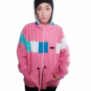 May include: A pink, blue and white colour block jacket with a zip fastening and a drawstring waist. The jacket has a hood and the brand name "Blue Sky" is visible on the front.
