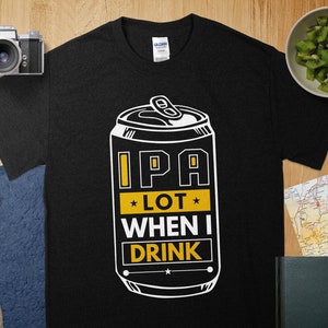 Pode incluir: Camiseta preta com um gráfico branco de uma lata de cerveja que diz "IPA Lot When I Drink".