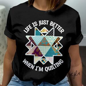 Peut inclure: T-shirt noir avec un motif graphique blanc représentant une étoile de patchwork et le texte "Life is just better when I'm quilting".
