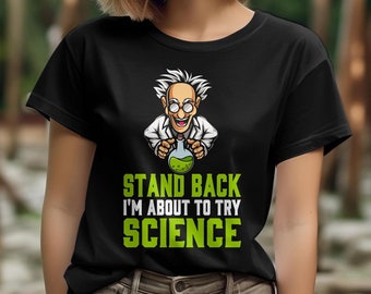 May include: Black t-shirt with a cartoon scientist holding a green liquid beaker. The text "STAND BACK I'M ABOUT TO TRY SCIENCE" is printed in green and white. The shirt is made of a soft material, suitable for casual wear.