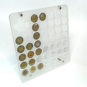Könnte beinhalten: Transparente Münz-Präsentationsplatte aus Acryl mit mehreren kreisförmigen Aussparungen, die verschiedene kanadische Münzen aufnehmen. Die Platte zeigt ein Ahornblatt-Design und ist mit Metallbeschlägen montiert. Das Wort "CANADA" ist unten rechts sichtbar.