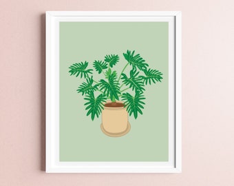 May include: A framed art print featuring a green plant with large, textured leaves in a beige pot. The plant is centered against a light green background, and the frame is white. The artwork is a botanical illustration.
