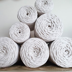 May include: A stack of six white cotton rope coils, arranged in a pyramid shape. The coils are made of thick, twisted cotton rope and have a natural, rustic look.