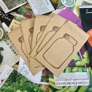 Puede incluir: Primer plano de cinco paquetes de semillas de papel marrón con un diseño de tarro de albañil. Los paquetes están dispuestos en forma de abanico y están rodeados de otros paquetes de semillas con varios nombres e imágenes de plantas.