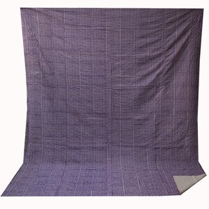 May include: A purple and white striped fabric with a repeating geometric pattern. The fabric is folded in half and the edges are visible.