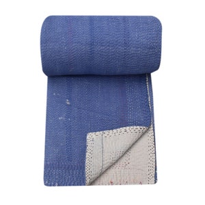 May include: A blue kantha quilt is rolled up and partially unfurled, revealing a white cotton lining. The quilt is made of a soft, lightweight fabric and is perfect for adding a touch of warmth and style to any room.
